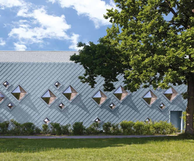 Zinc roof and cladding creates sculptural facade for sports hall