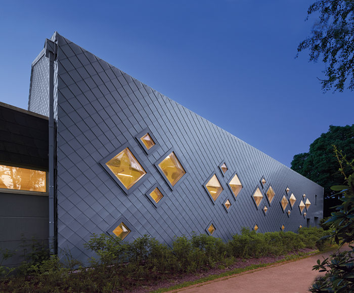 Zinc roof and cladding creates sculptural facade for sports hall | Images
