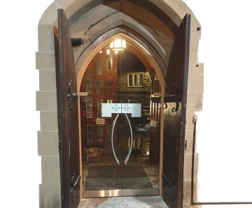 Automated entrance with concealed underfloor drives for historic church